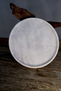 Round marble tray with natural veining displayed against driftwood