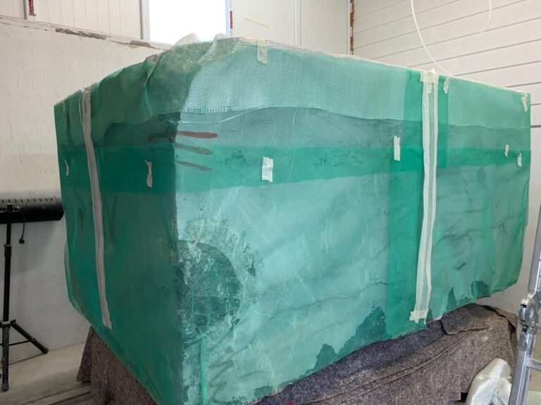 Marble block wrapped in green protective mesh before cutting in Turkey