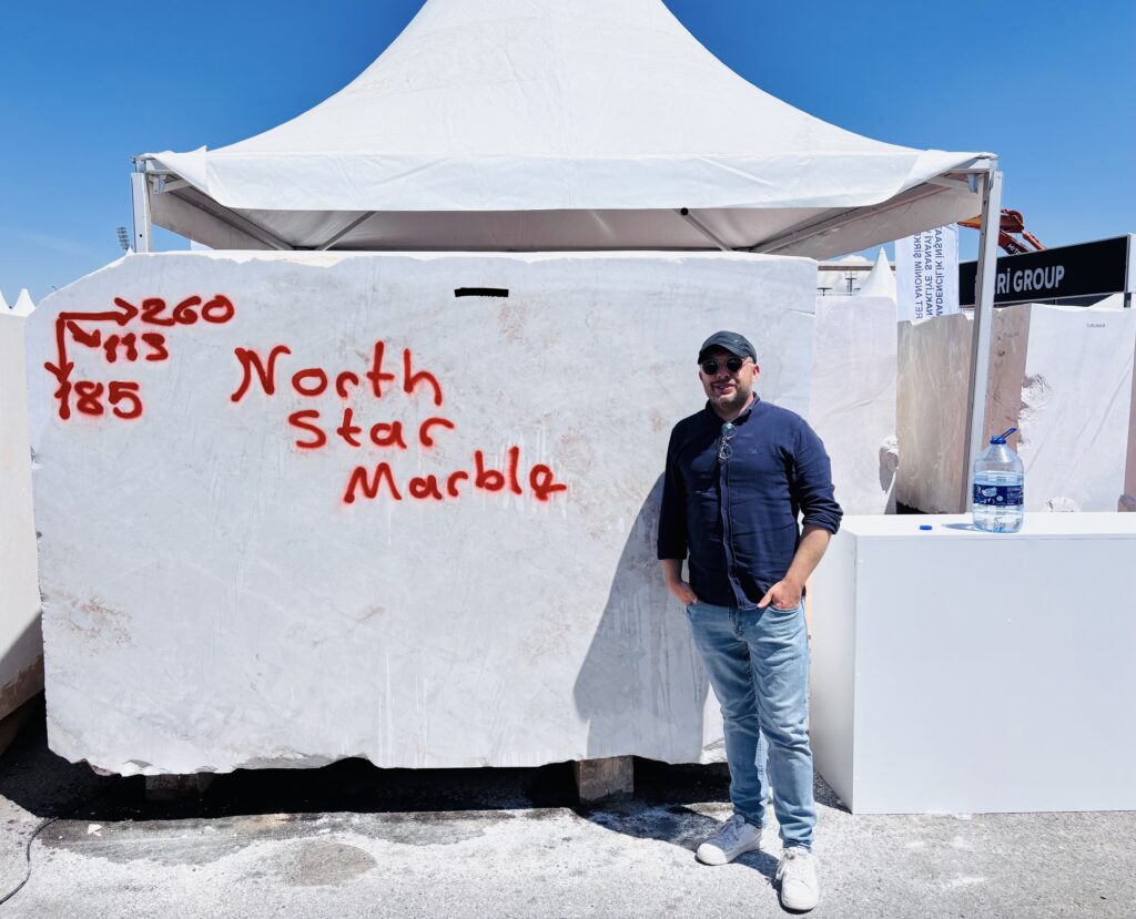 Oğuz Sücüllü of North Star Marble standing next to a selected marble block marked North Star Marble