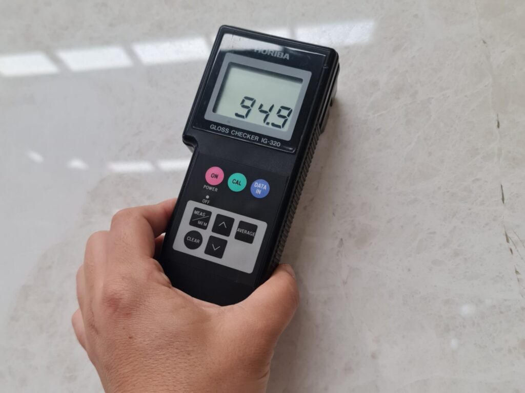 Gloss meter held against a polished vanilla marble slab to check the finish