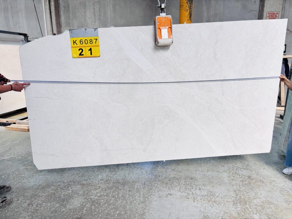Marble slab on a crane being measured with a tape during size inspection