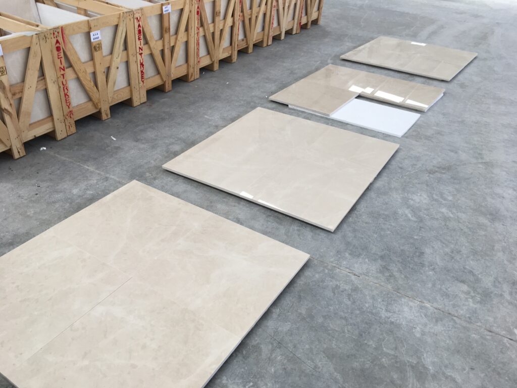 Polished marble tile samples laid on a factory floor next to wooden crates marked Made in Turkey
